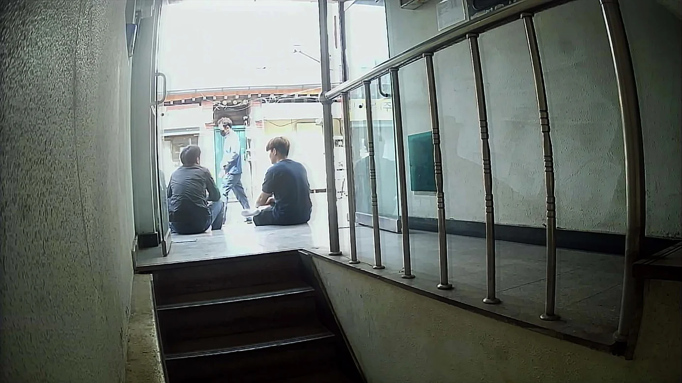 Three people sitting and standing at the entrance to a building