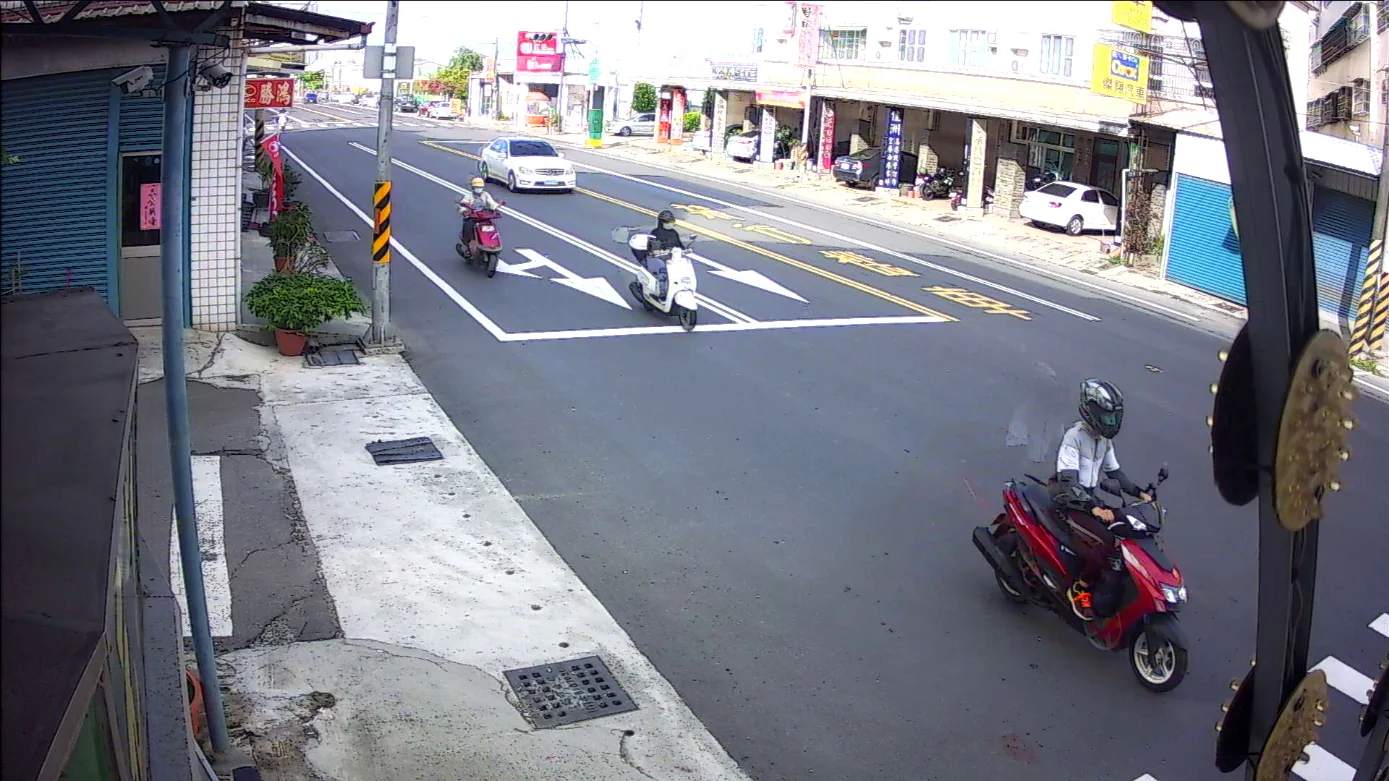 Network surveillance camera view of scooters passing through a city street