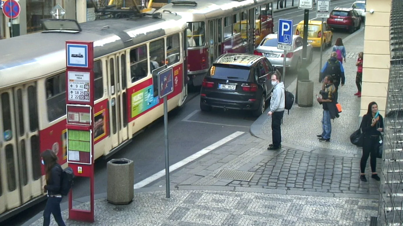 Pedestrians waiting beside trams on a city street