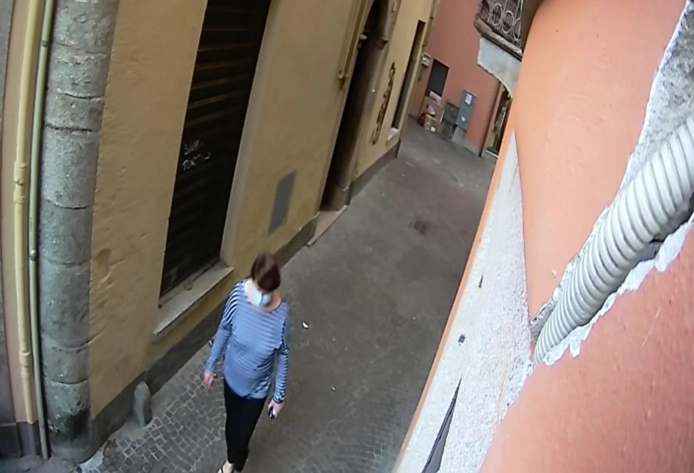 A masked pedestrian walking through a narrow alley