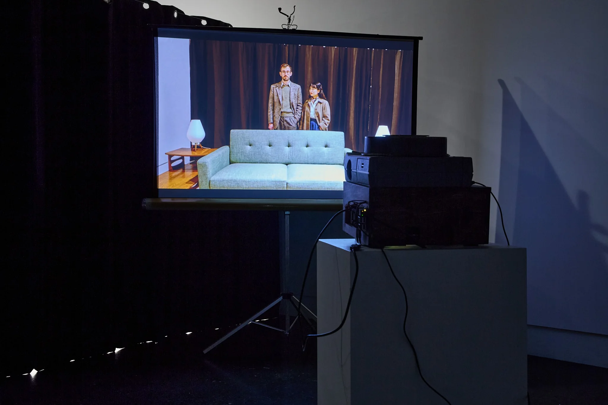 Modified vintage projector apparatus facing a screen that displays visitors inside the living room